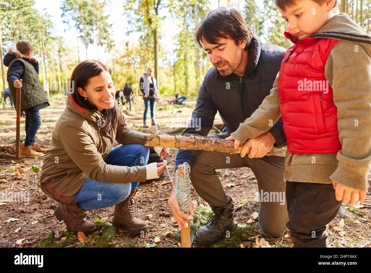 Forester and family with child hitting the stake in the forest for environmental protection and sustainability Stock Photo