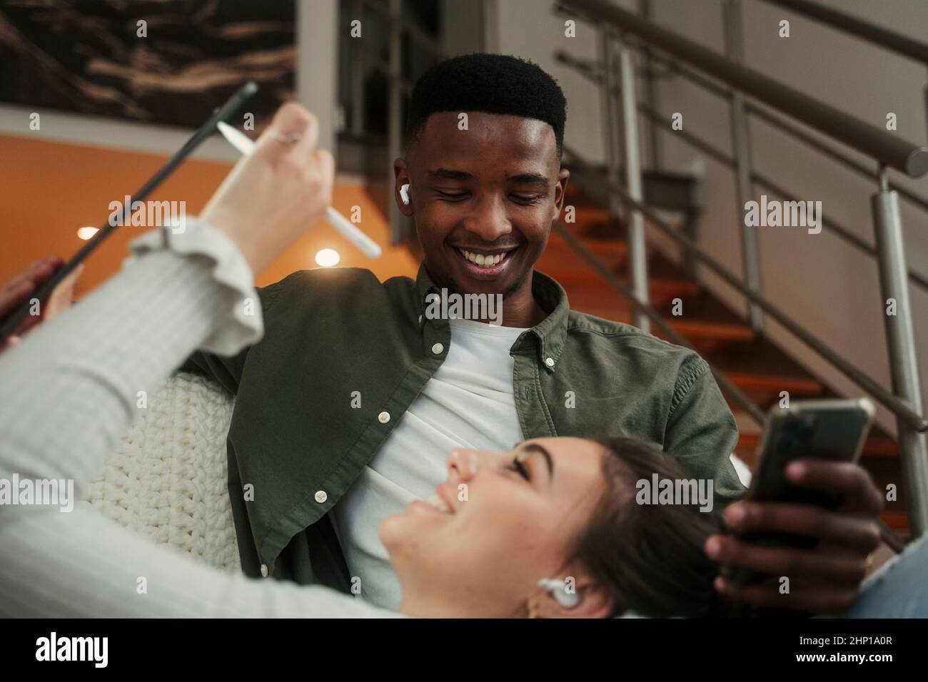 Biracial couple relaxing together on couch while using technology  Stock Photo