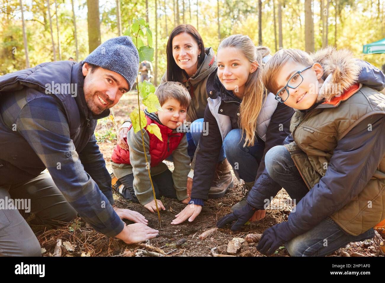 Family and children plant trees in the forest together for conservation and sustainability Stock Photo