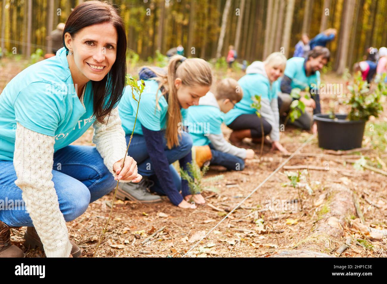 Group of volunteers and children planting trees for sustainable reforestation in the forest Stock Photo