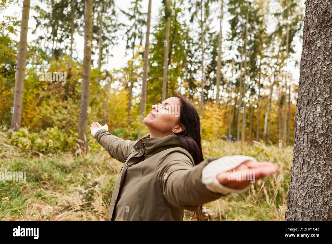 Relaxed woman doing calm breathing exercise in forest with arms outstretched Stock Photo