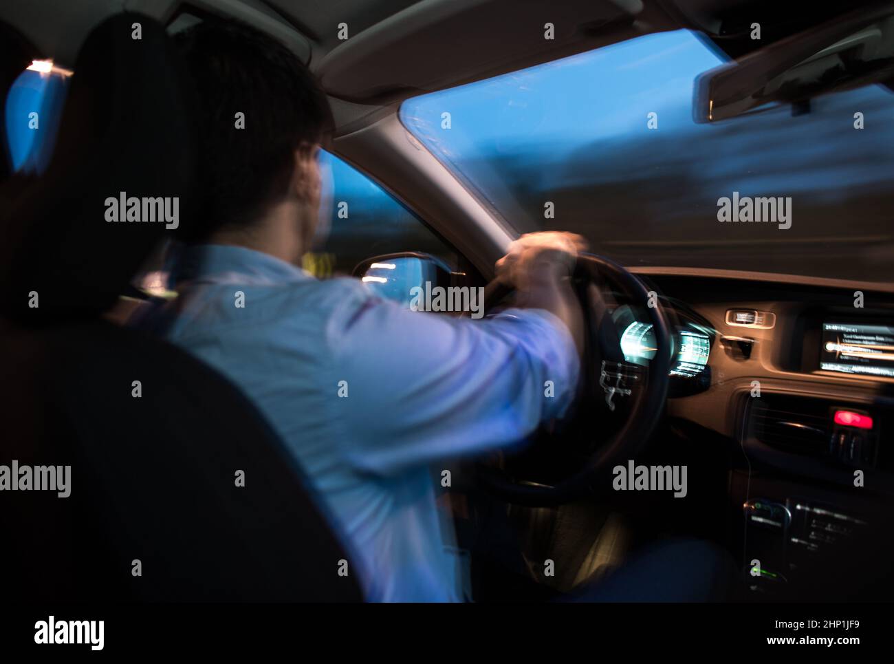 Driving a car at night - young man driving his modern car at night in a ...