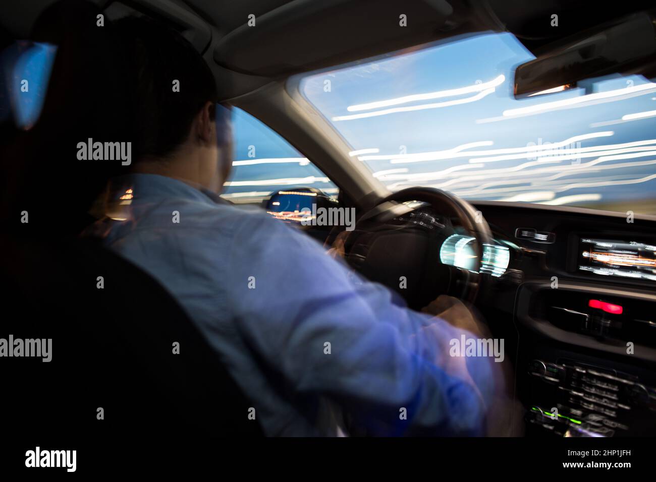 Driving a car at night - young man driving his modern car at night in a ...