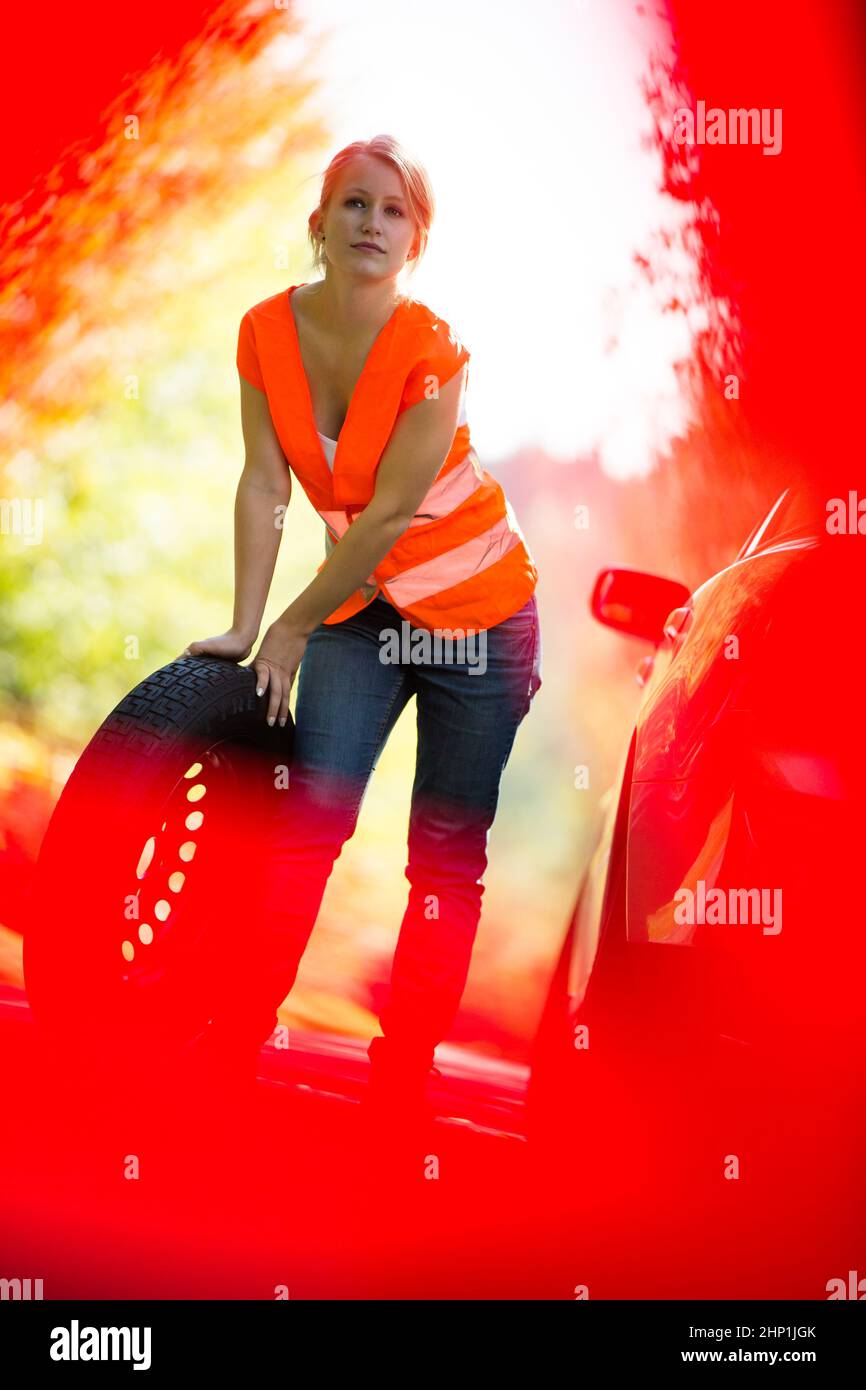 Young female driver wearing a high visibility vest, calling the roadside service/assistance after her car has broken down Stock Photo