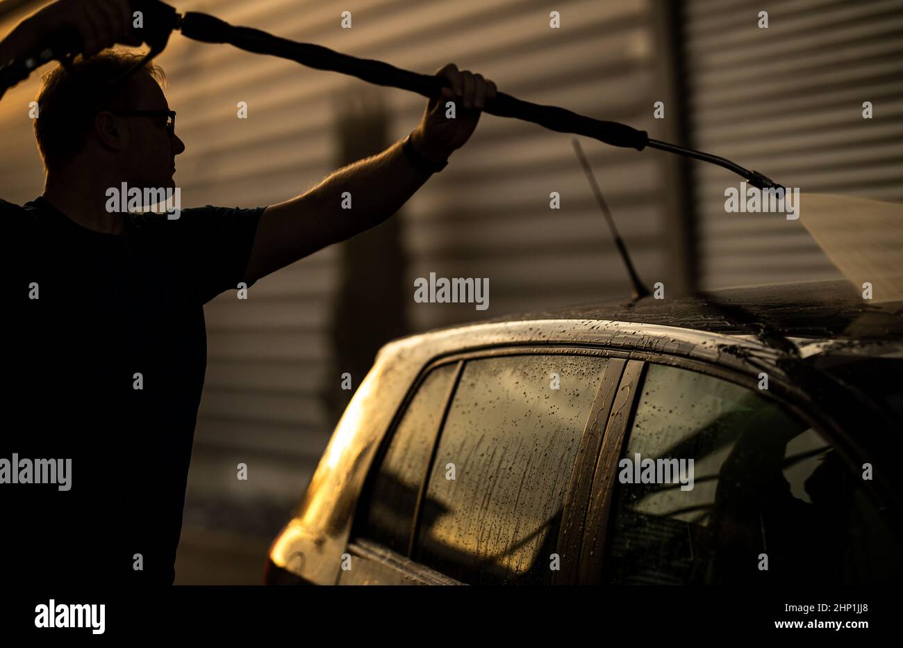 Young man washing his beloved car carefully in a manual car wash to