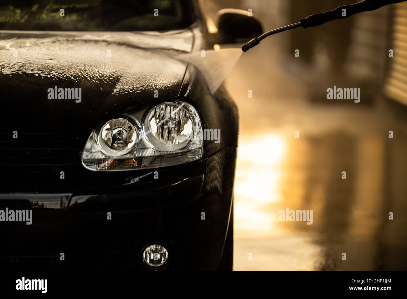 Young man washing his beloved car carefully in a manual car wash to