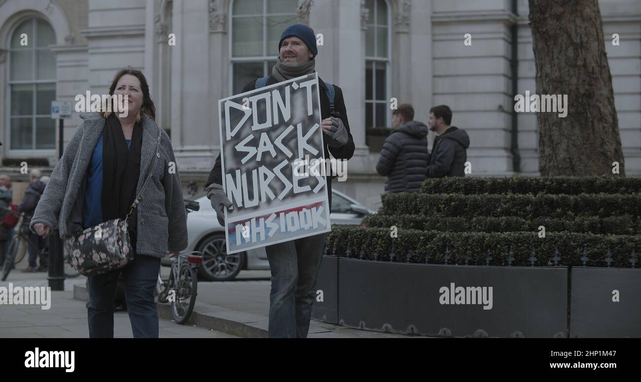 London, UK - 01 22 2022:  A male protester walking at Portland Place holding a sign, ‘Don’t Sack Nurses, NHS100K’. Stock Photo