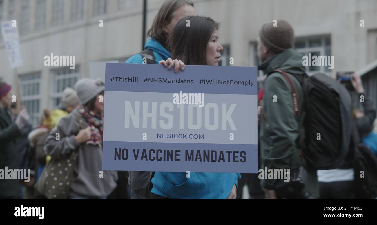 London, UK - 01 22 2022: NHS worker holding a sign, ‘NHS100K, No Vaccine Mandate’, whilst marching with a crowd of protesters. Stock Photo