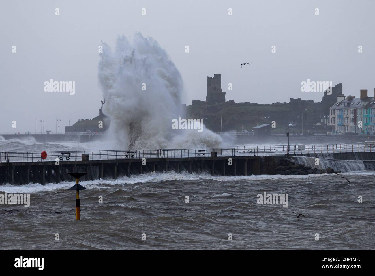Aberystwyth, UK. 18th Feb, 2022. 18 February 2022, Aberystwyth, Wales, UK. Storm Eunice. Gale force winds cause very rough seas at high tide on the mid Wales coast. Huge waves pummel the the promenade and sea defences at the mouth of Aberystwyth harbour. Credit: atgof.co/Alamy Live News Stock Photo