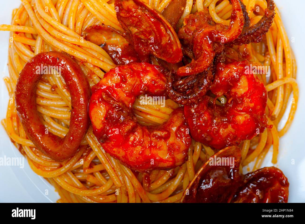 Italian seafood spaghetti pasta on red tomato sauce over white rustic