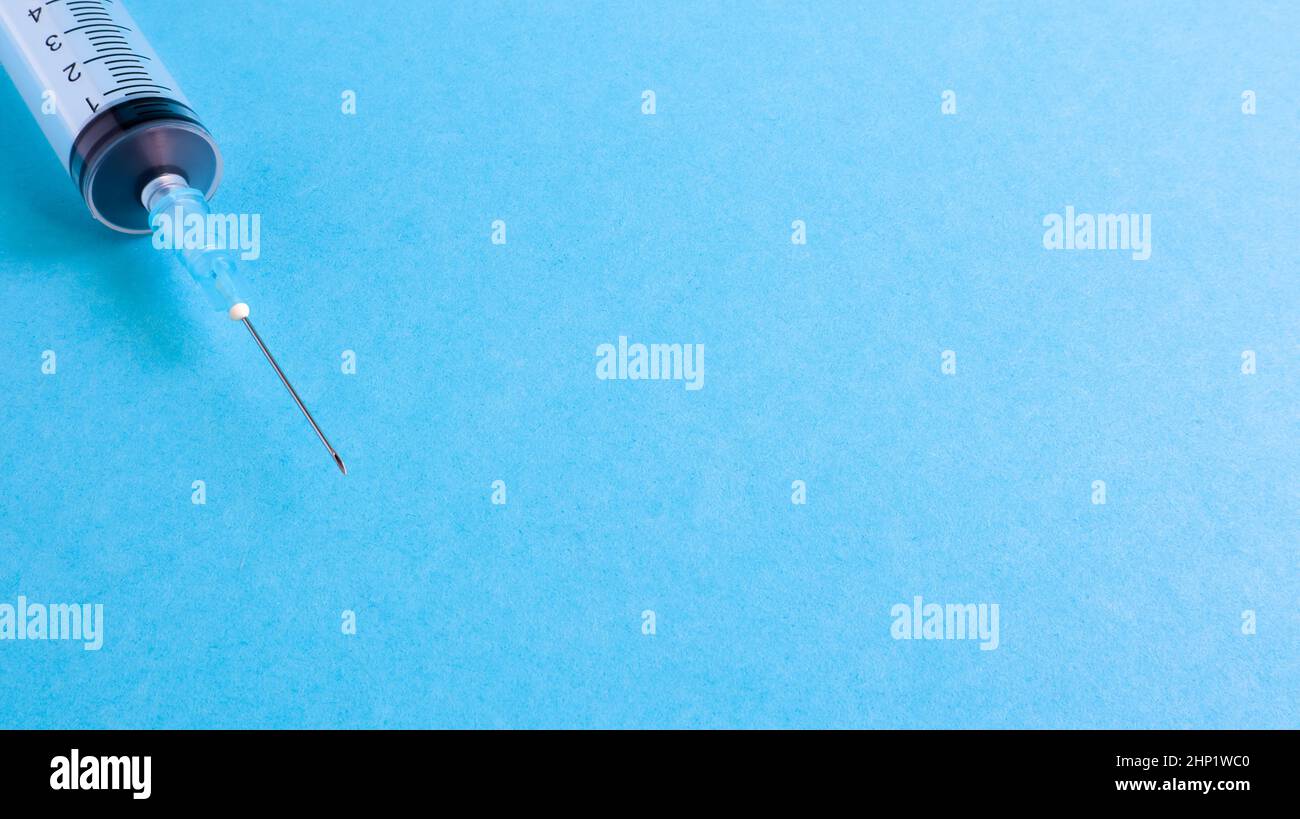 On a blue background lies a medical syringe with a needle. epidemic ...