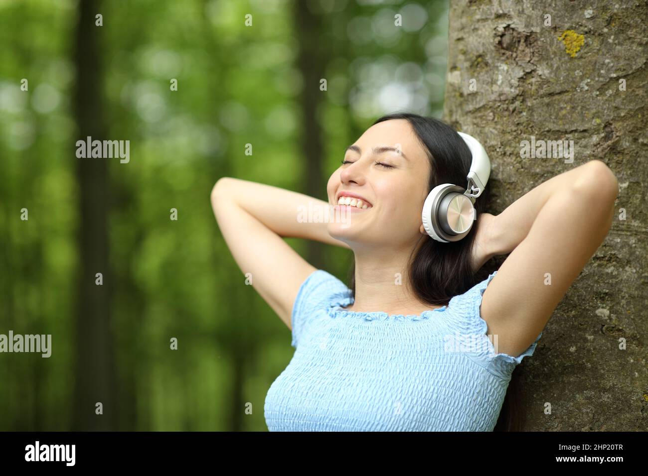 Happy asian woman listening to music wearing headphones in a park Stock ...