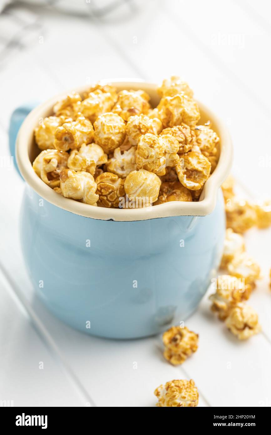 Sweet caramel popcorn in cup on white table. Stock Photo