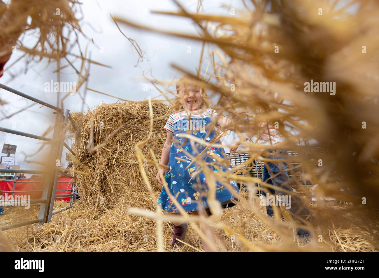 Young girls playing in a bale of straw at an agricultural show, Kelso, Scottish Borders, UK. Stock Photo