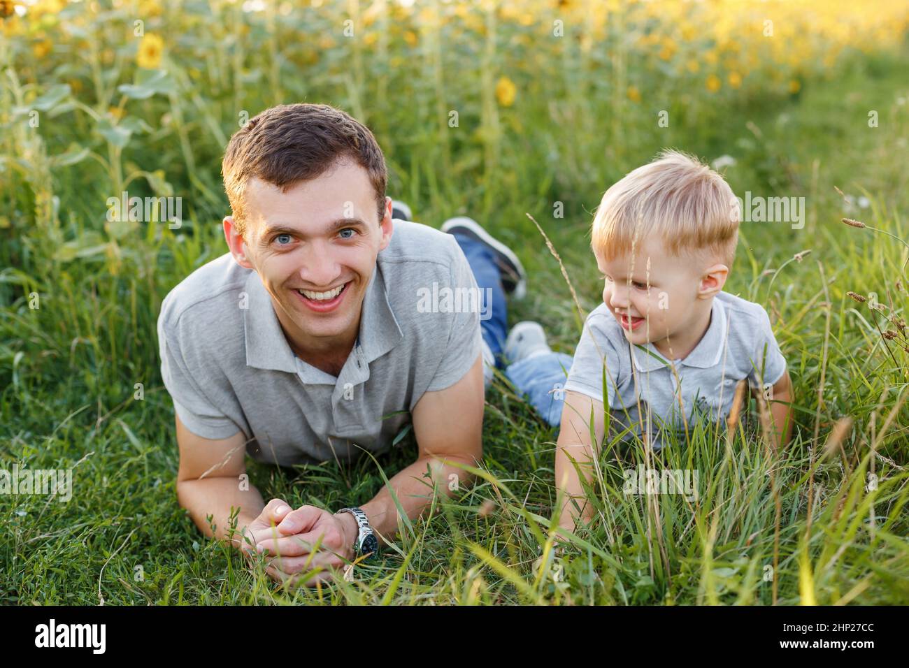 Father and son having fun on the grass. Little boy and his dad lying and laughing. Summer outdoors lifestyle, family leisure, parenthood Stock Photo