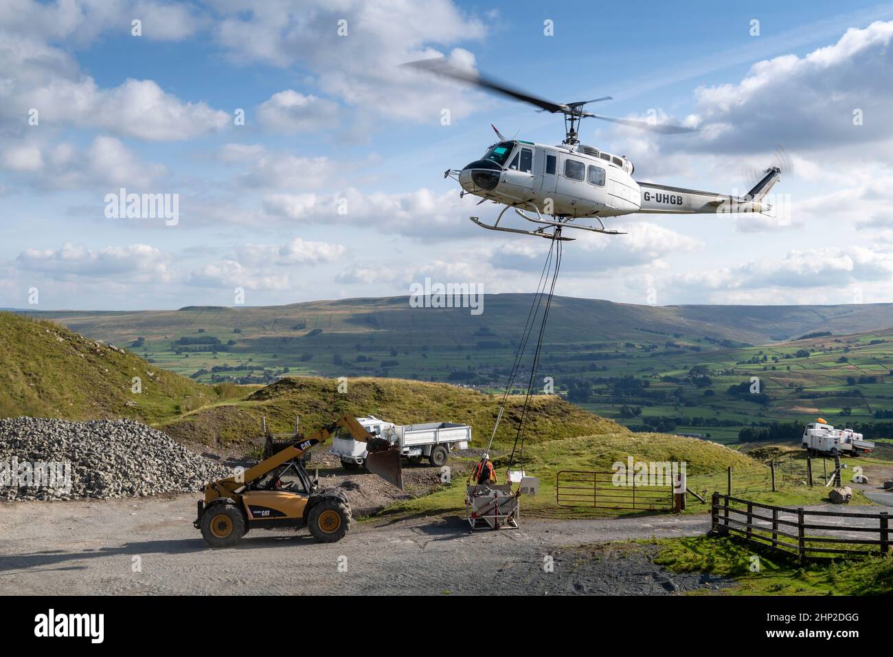 Helicopter carrying a load of stone to take up onto moorland to be used to help restore peatland in the Yorkshire Dales, UK. Stock Photo