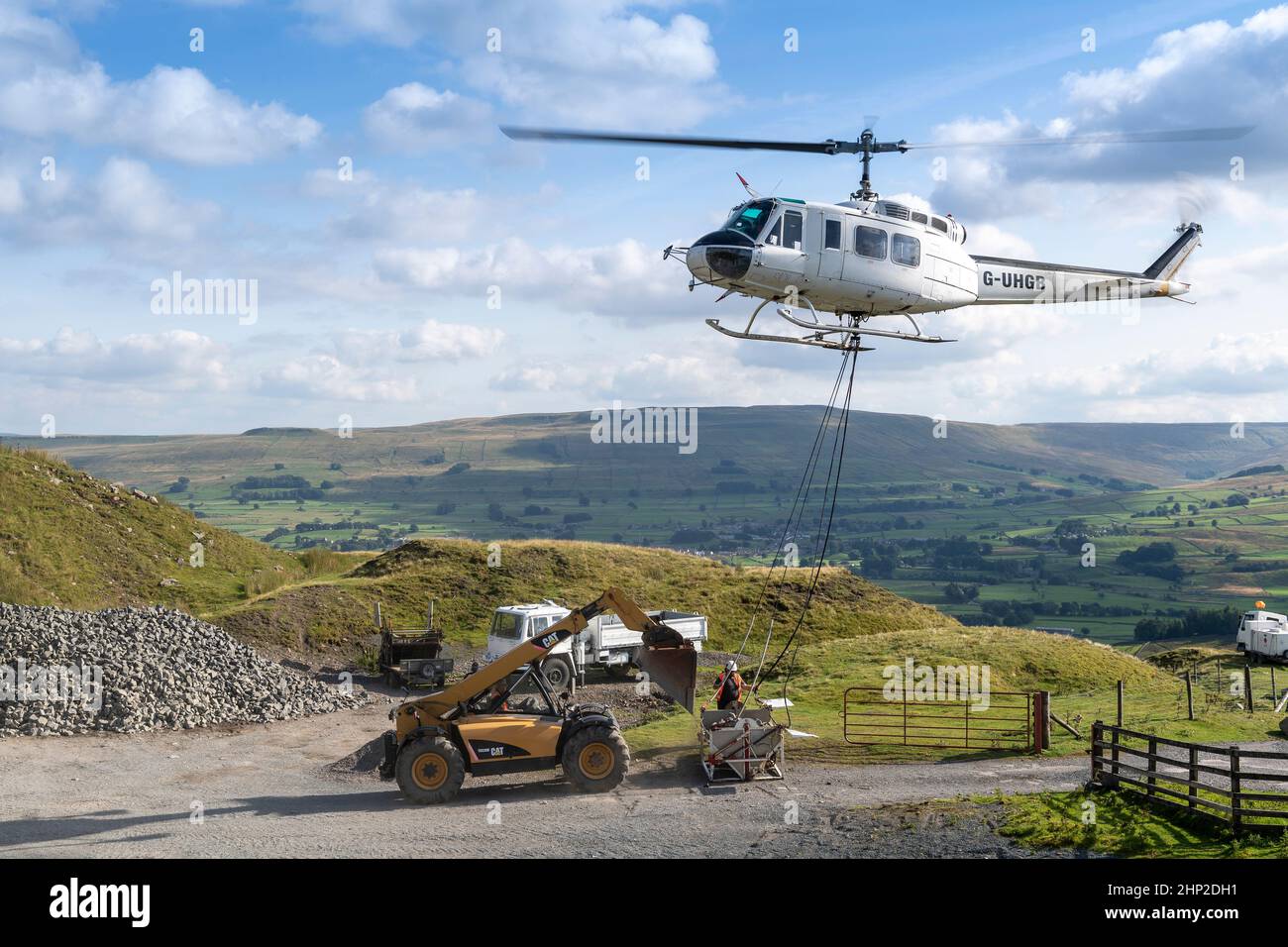 Helicopter carrying a load of stone to take up onto moorland to be used to help restore peatland in the Yorkshire Dales, UK. Stock Photo