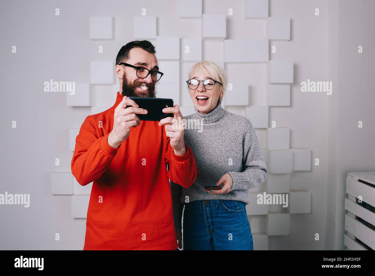 Happy modern startup colleagues sharing smartphone Stock Photo