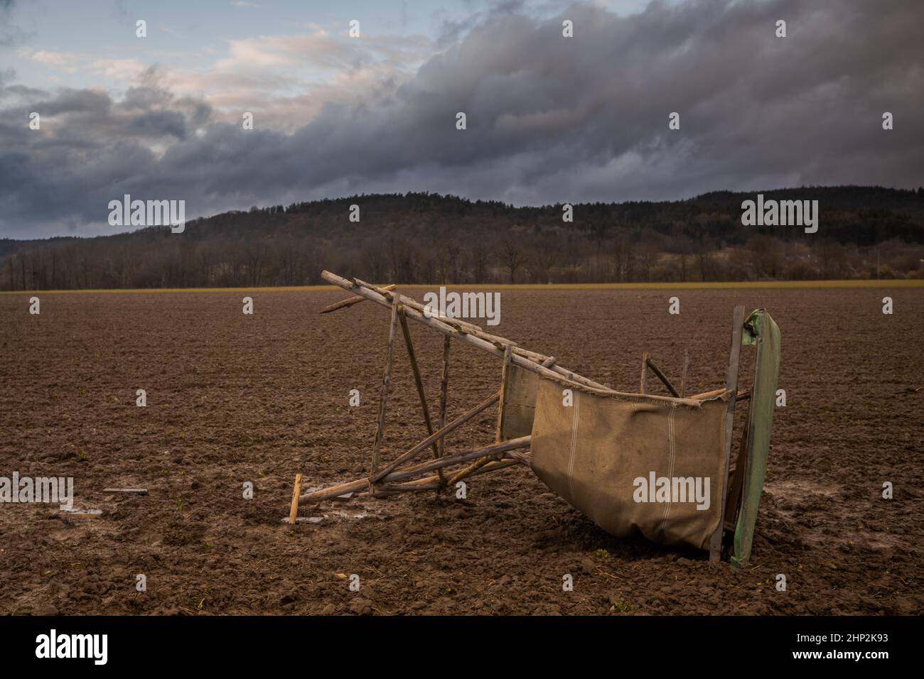 Raised wooden hunting blind lying sideways on barren field blown over by heavy wind after strong storm Stock Photo