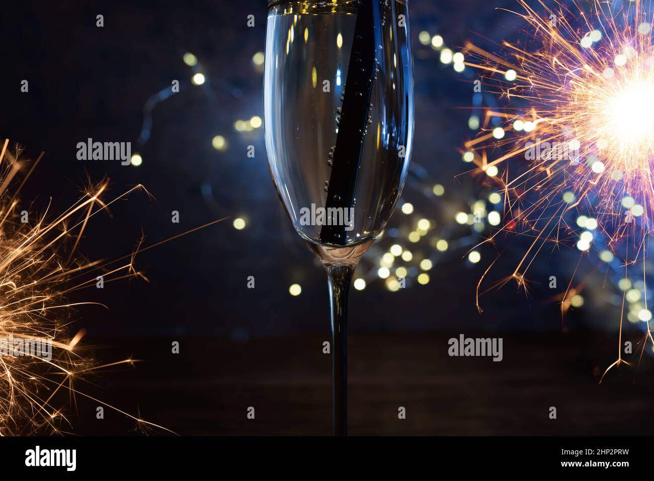 Celebration with sparkeling champagne. New year's eve background with sparkler and festive golden bokeh. Close-up. Stock Photo