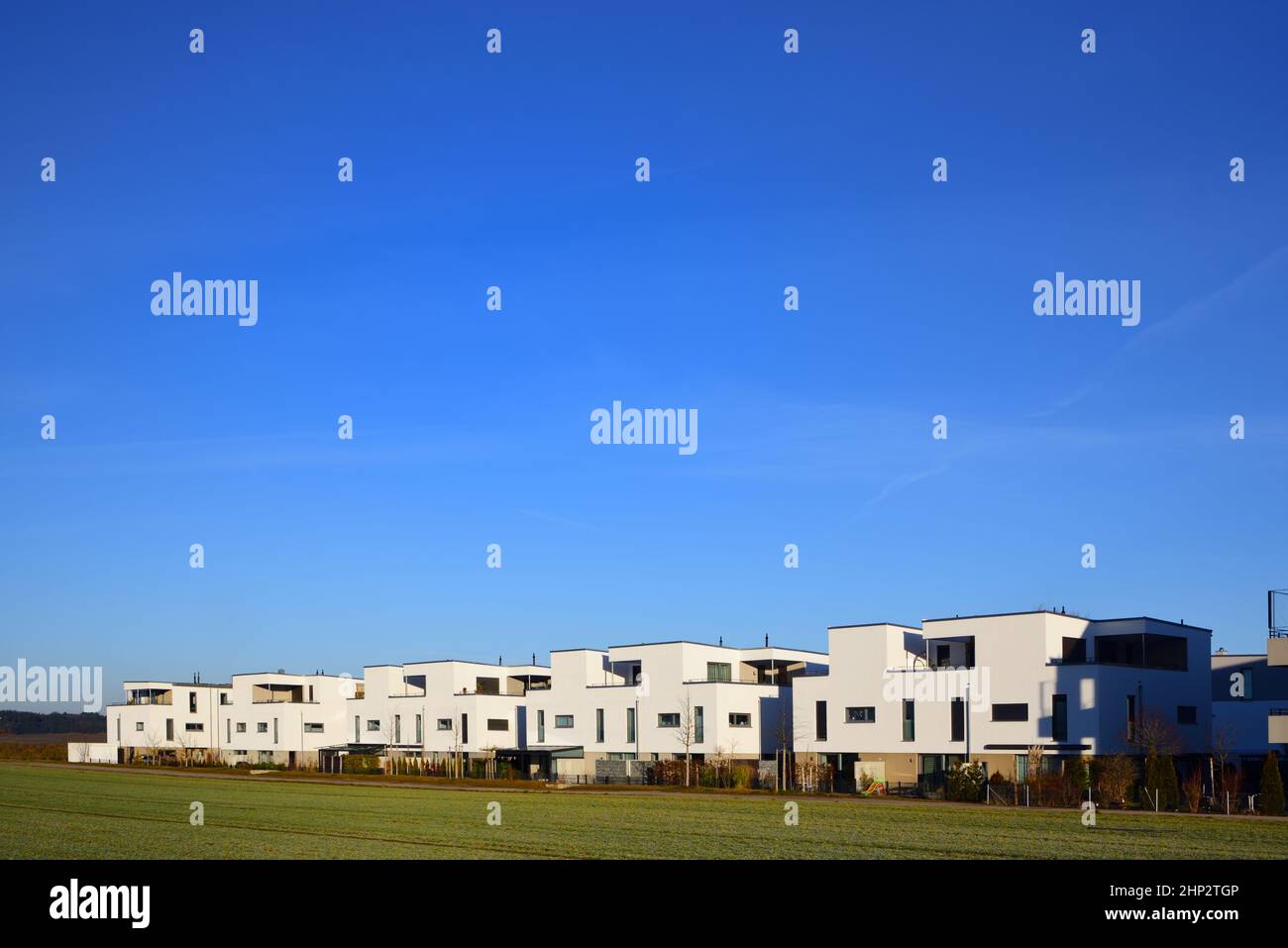 Scenic shot of new single family homes forming a small settlement on the edge of a green space against a backdrop of plenty of blue sky with room for Stock Photo