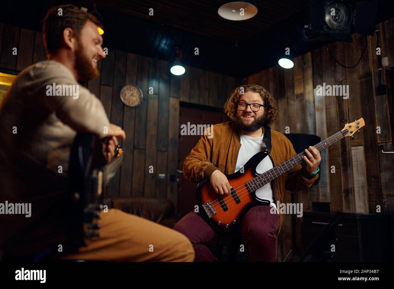 Two young adult male friends playing electric guitars at studio. Improvised rock band. Music lesson Stock Photo
