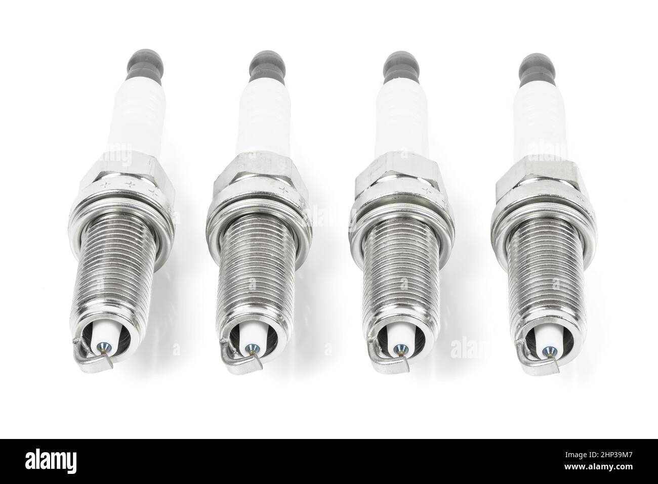 Four iridium spark plugs in a row isolated on white background with clipping path Stock Photo