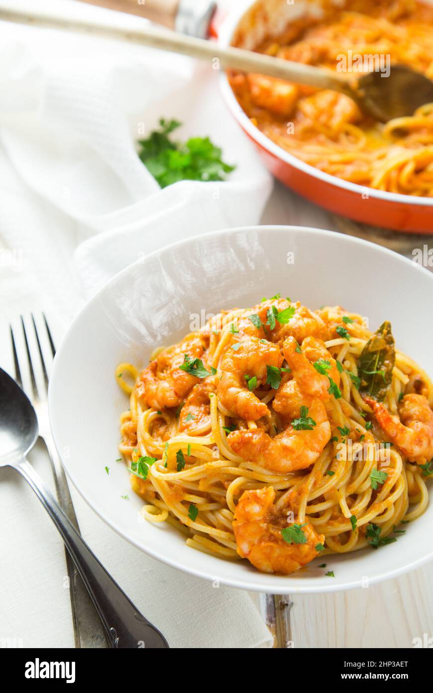 Italian shrimp and tomato sauce pasta in a white bowl in a light ...