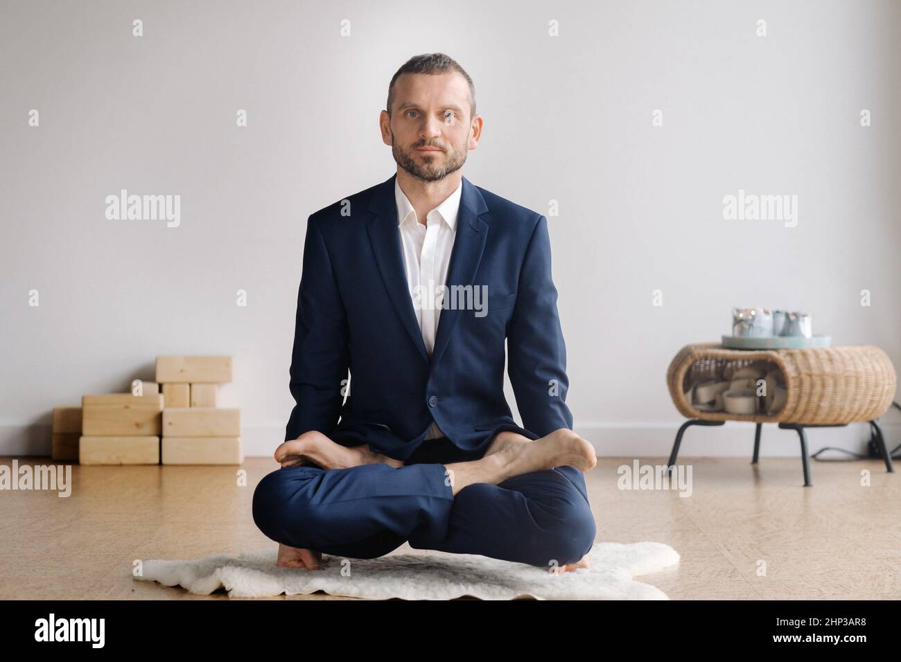 A man in a strict suit does Yoga while sitting in a fitness room Stock Photo