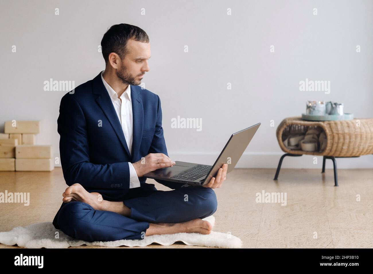 A man in a formal suit works sitting in a fitness room on a laptop Stock Photo