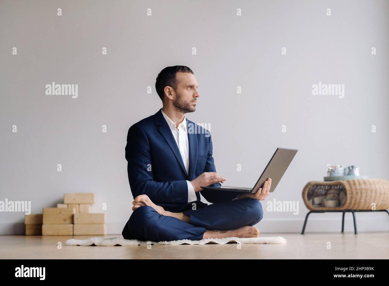 A man in a formal suit works sitting in a fitness room on a laptop Stock Photo