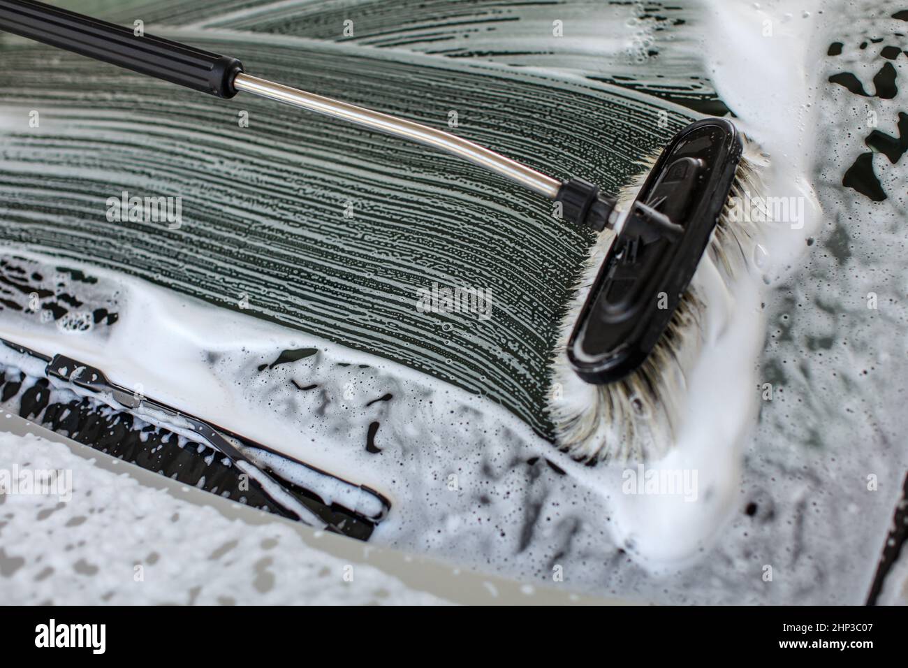 Brush leaving strokes in shampoo and foam on windshield of a car washed