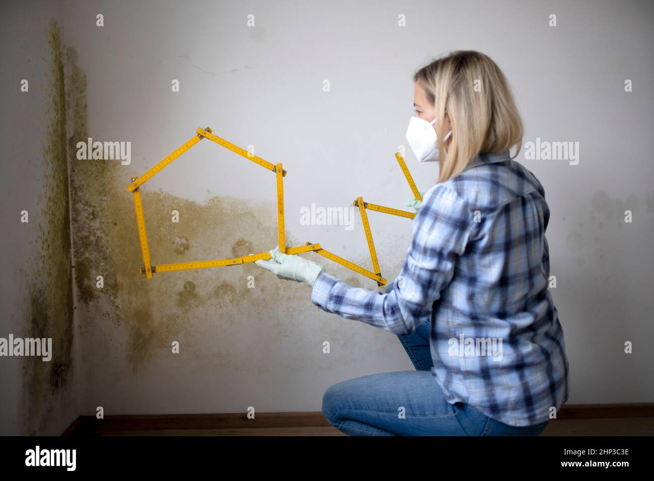 young woman standing in front of wall with mold with folding rule and