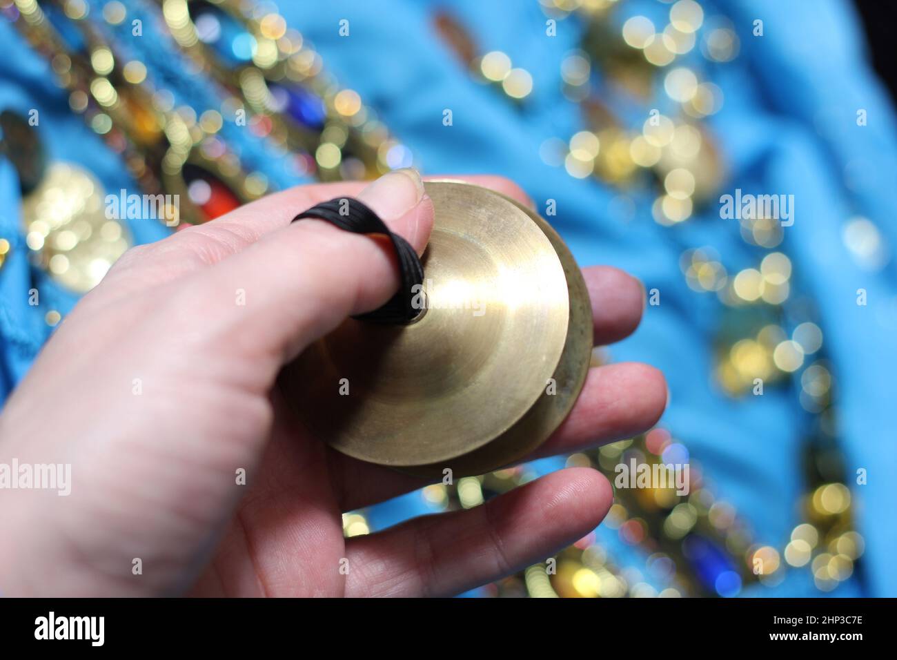 Belly dancer hand close up with finger cymbal with dance costume in