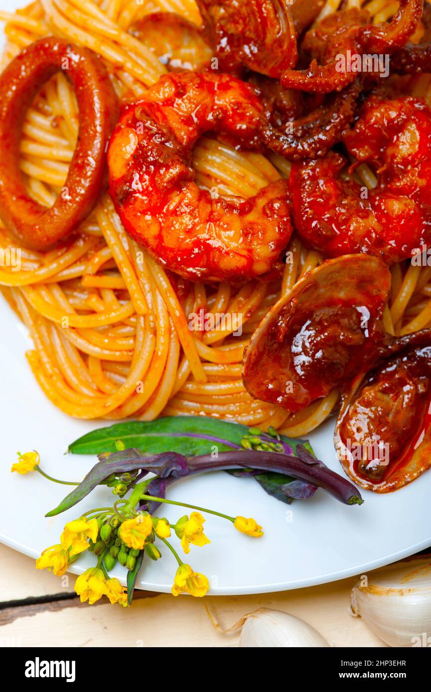 Italian seafood spaghetti pasta on red tomato sauce over white rustic