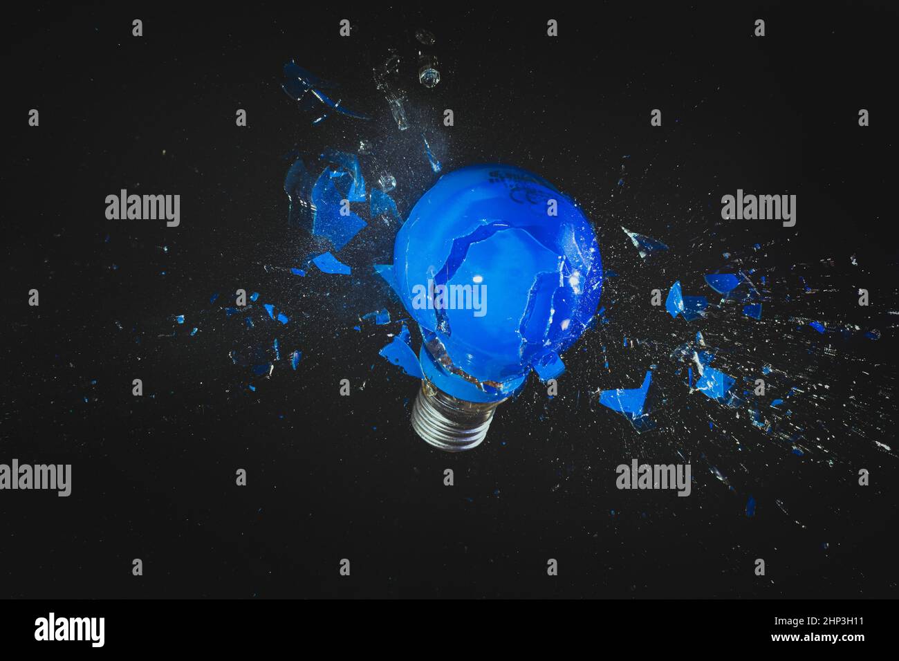 blue light bulb exploding on black. fragility concept Stock Photo Alamy