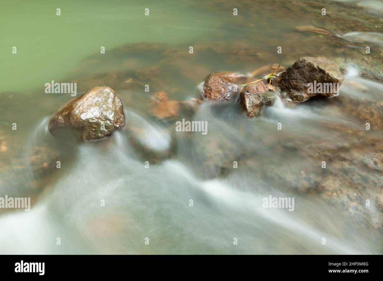 Rocks in stream with smooth flowing water with long exposure technique ...