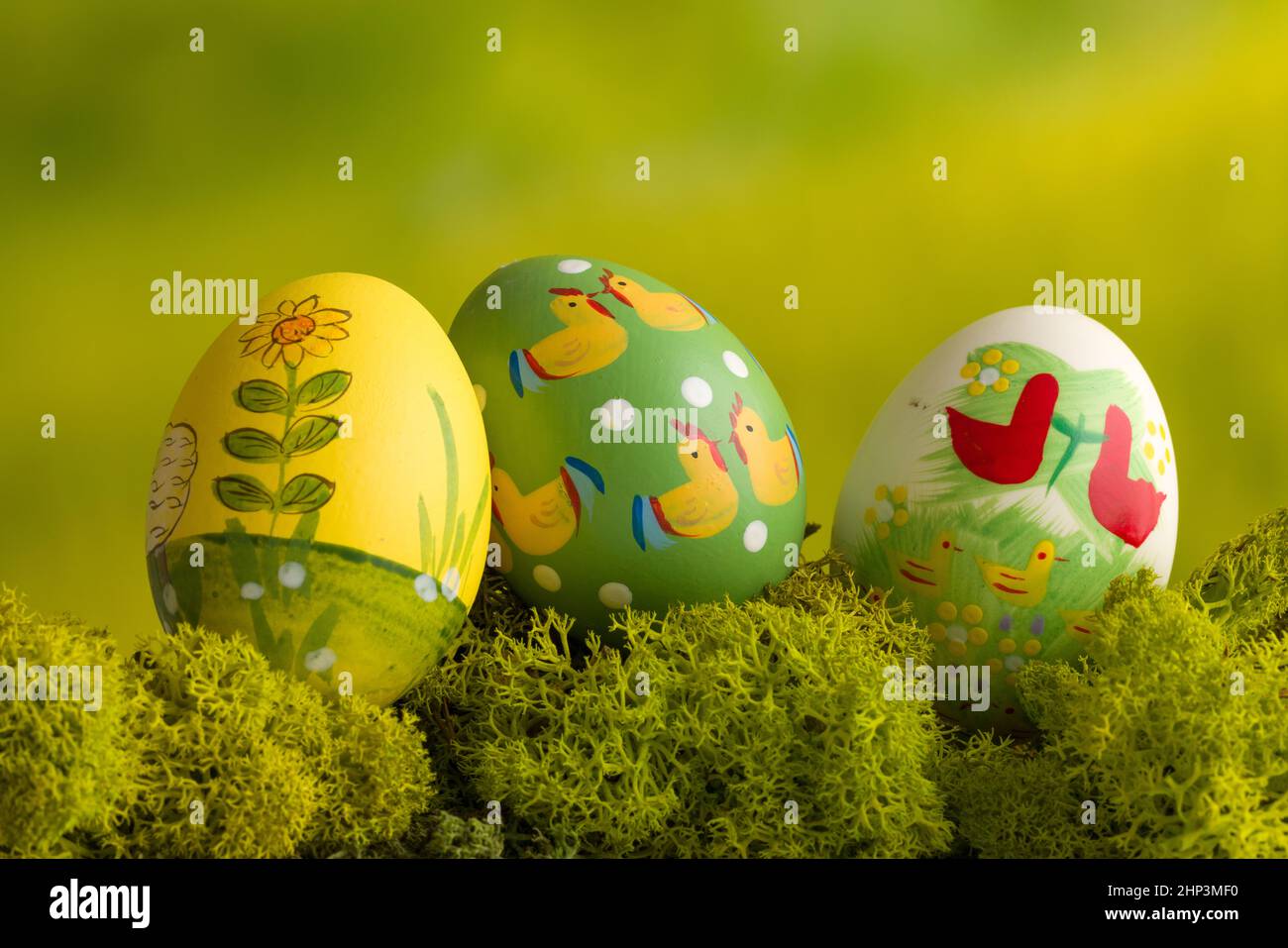 Three multi colored easter eggs on a mossy green background Stock Photo