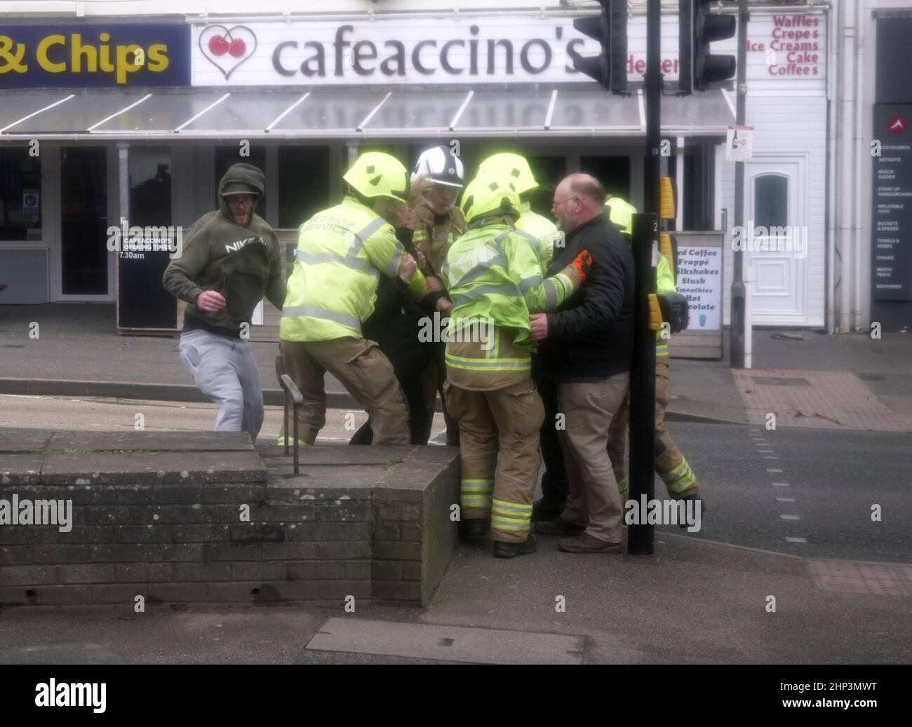 Newquay, UK. 18th February 2022. Eunice Red zone coastal town bears brunt of the storm. A woman was knocked down on the Narrowcliff road by severe wind and clung to a rail until passers by rushed to her aid, a team from Cornwall fire and Rescue were securing loose shop fronts nearby and seeing the situation dashed to take control.  Robert Taylor Alamy Live News Stock Photo