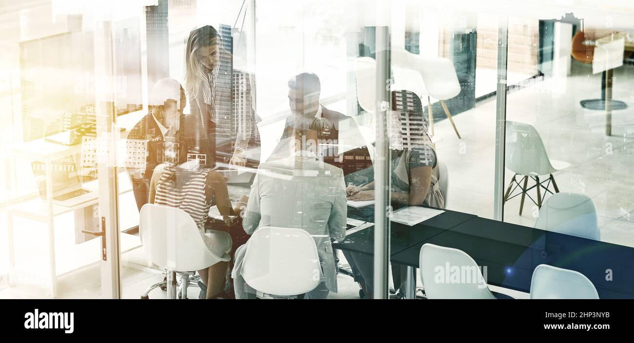 Getting down to business in the city. Multiple exposure shot of businesspeople in an office superimposed on a cityscape. Stock Photo