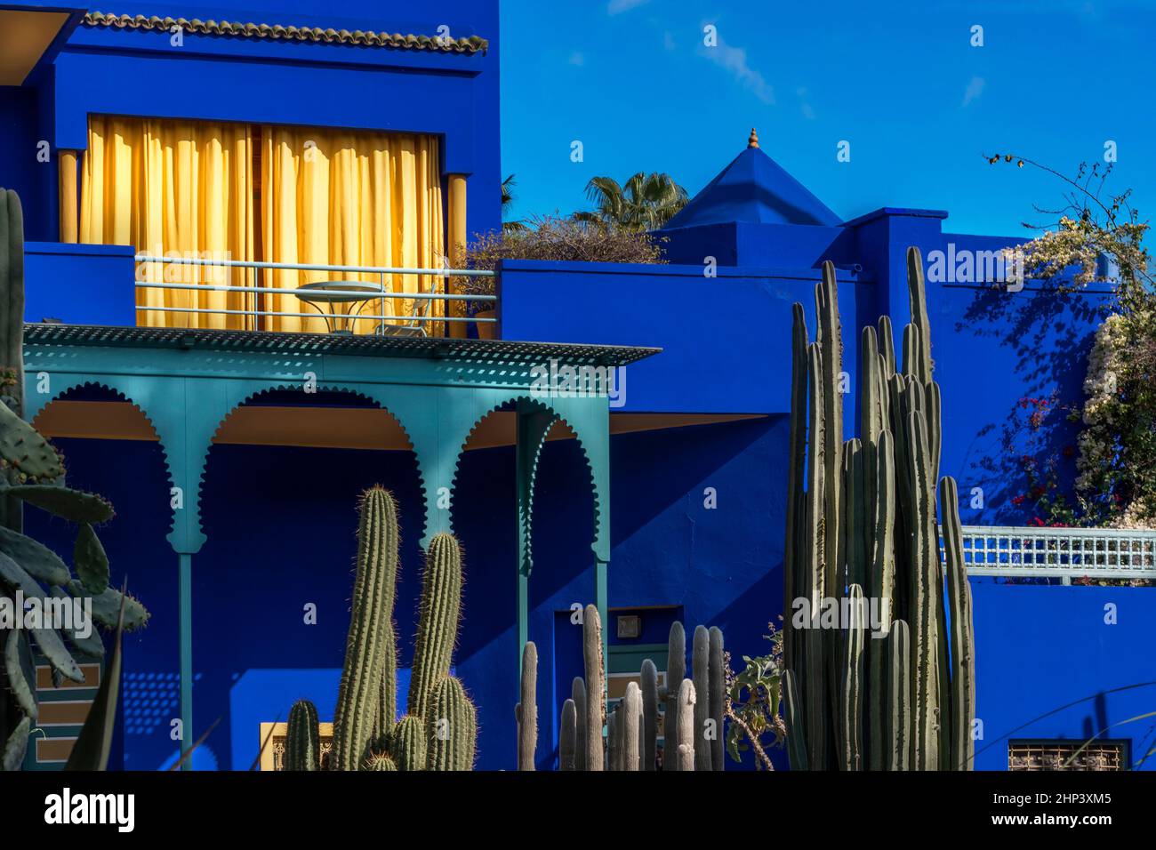 MOROCCO MARRAKESH THE MAJORELLE GARDEN حديقة ماجوريل  HOUSE WITH COBALT BLUE WALLS  BRIGHT YELLOW CURTAINS AND CACTI Stock Photo