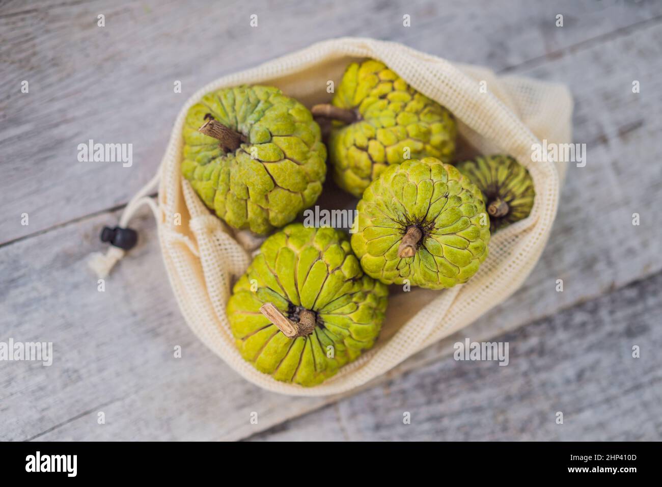 Cherimoya in a reusable bag on a stylish wooden kitchen surface. Zero waste concept, plastic free concept. Healthy clean eating diet and detox. Summer Stock Photo