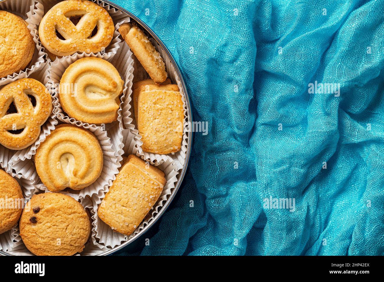 Tasty danish butter cookies in a tin over crumpled turquoise cloth