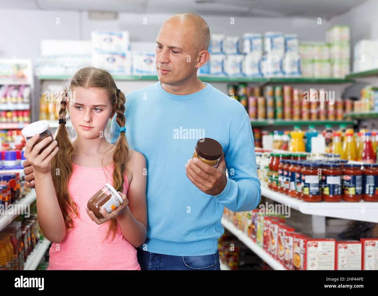 Girl with father choosing different goods in supermarket Stock Photo