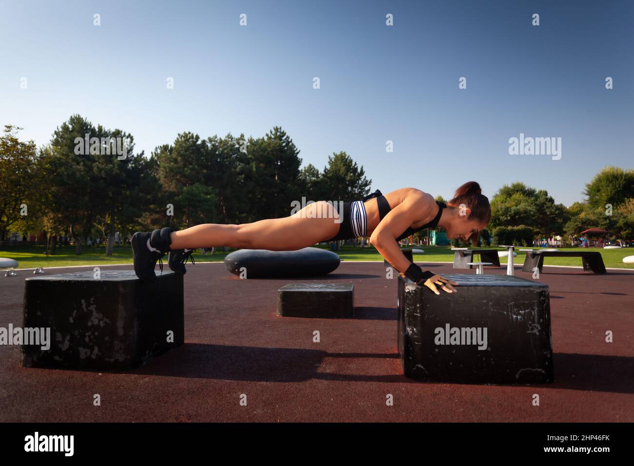 Young fitness woman doing push ups in the park Stock Photo - Alamy