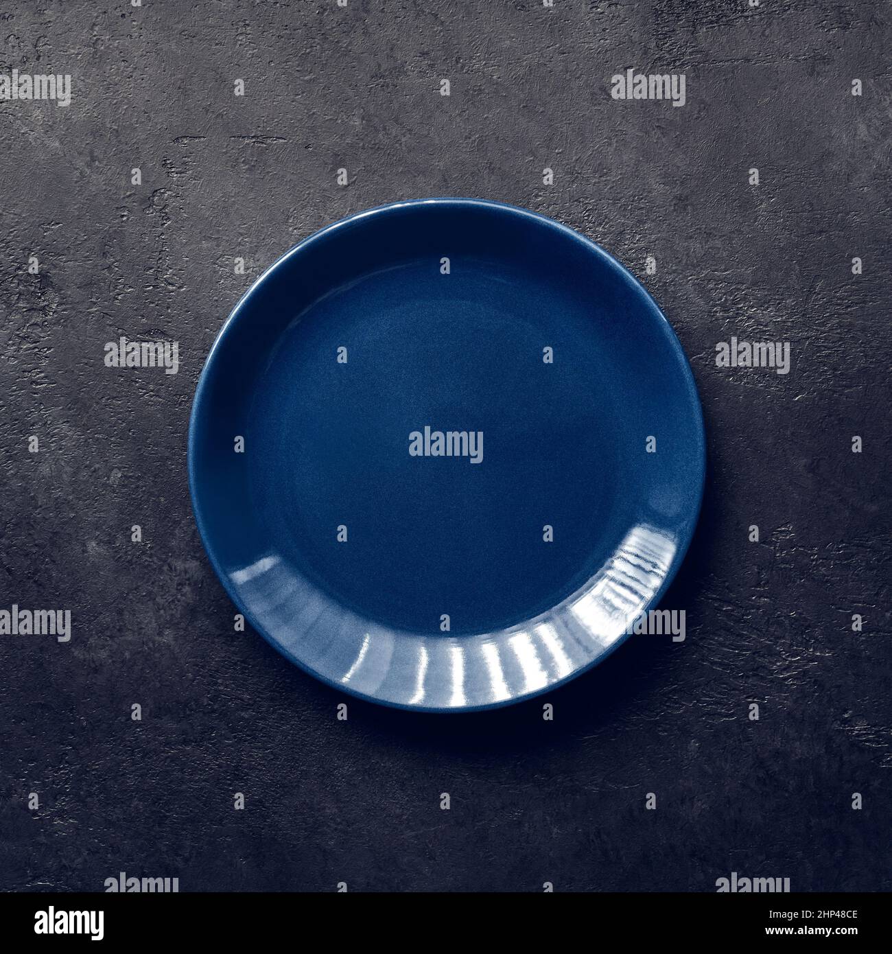 Empty blue plate on black background, vintage toning Stock Photo