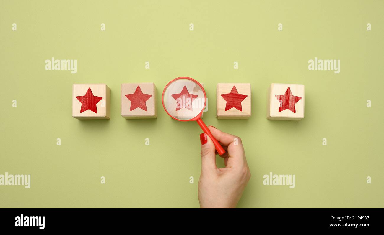 five red stars and a hand with a plastic magnifier on a green background.  Evaluation of the quality of services and goods, high rating Stock Photo -  Alamy