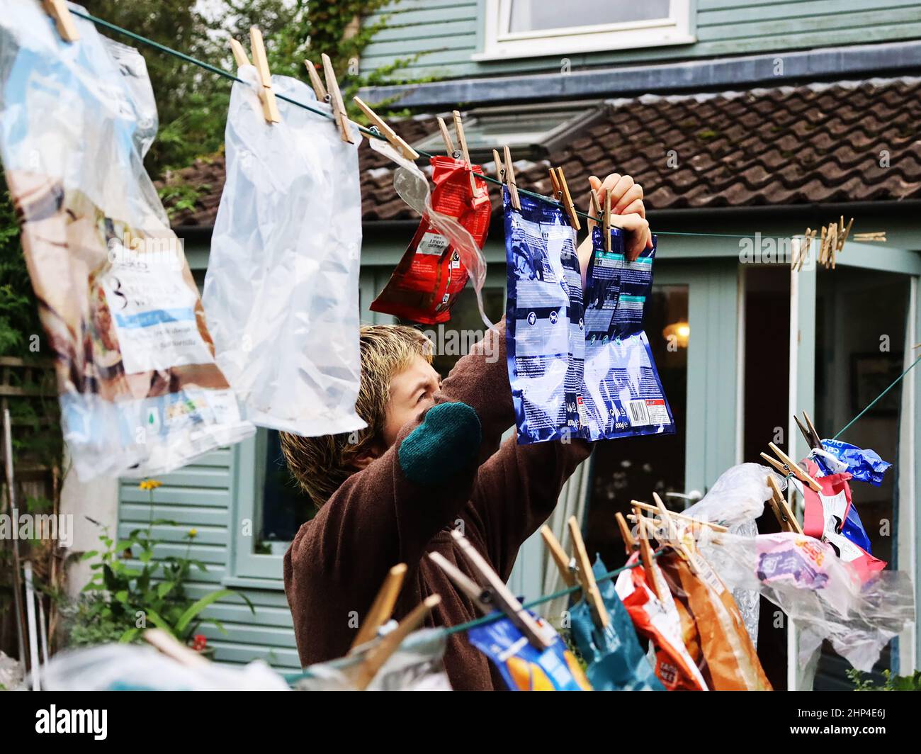 Colour photo of someone hanging plastics on a washing line, inspired by responses to climate change. Stock Photo