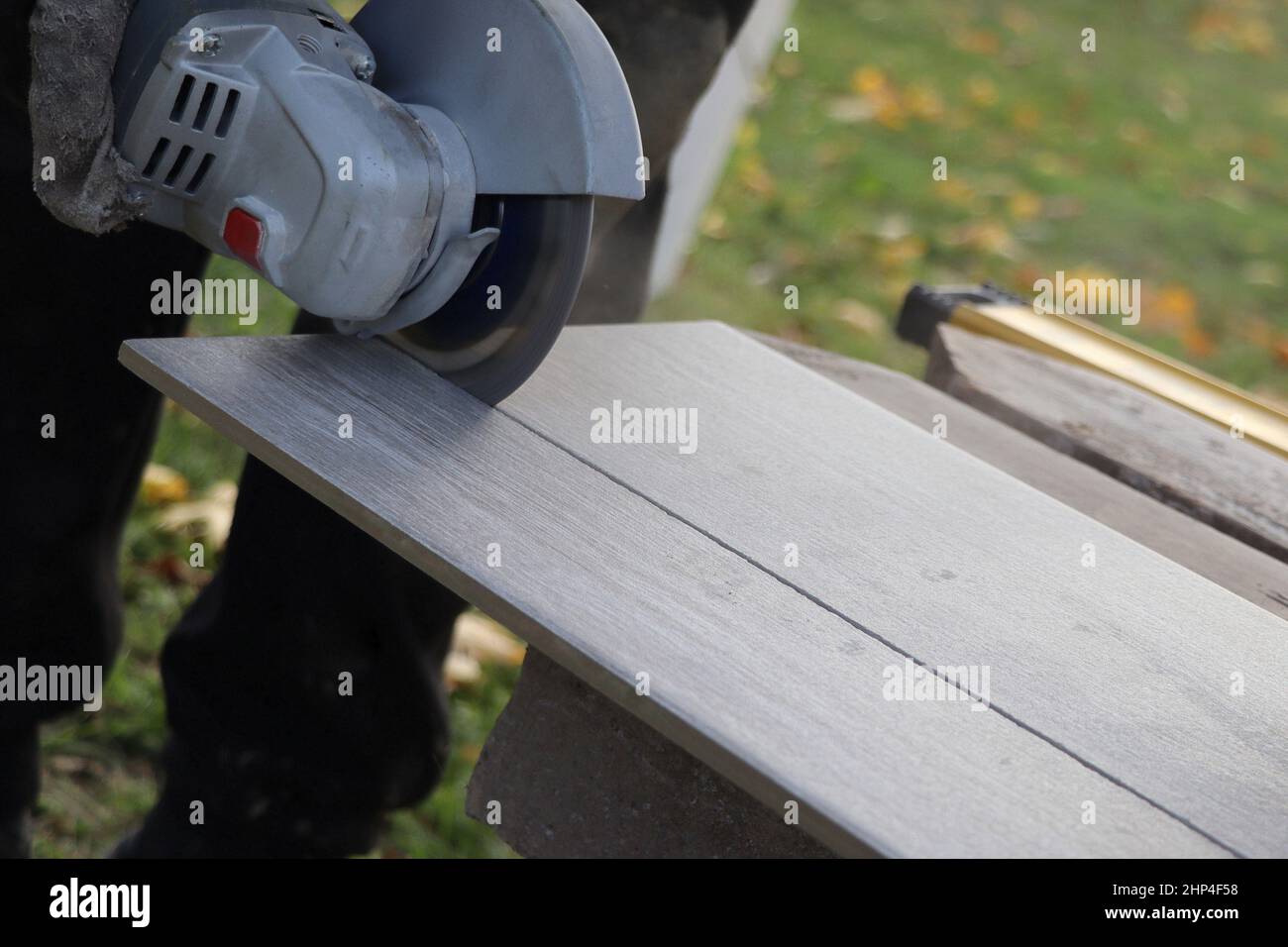 worker cutting a tile using an angle grinder at construction site Stock Photo