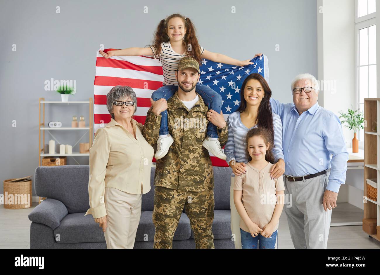 Portrait of a military father and his big happy family with an American flag in his hands. Stock Photo